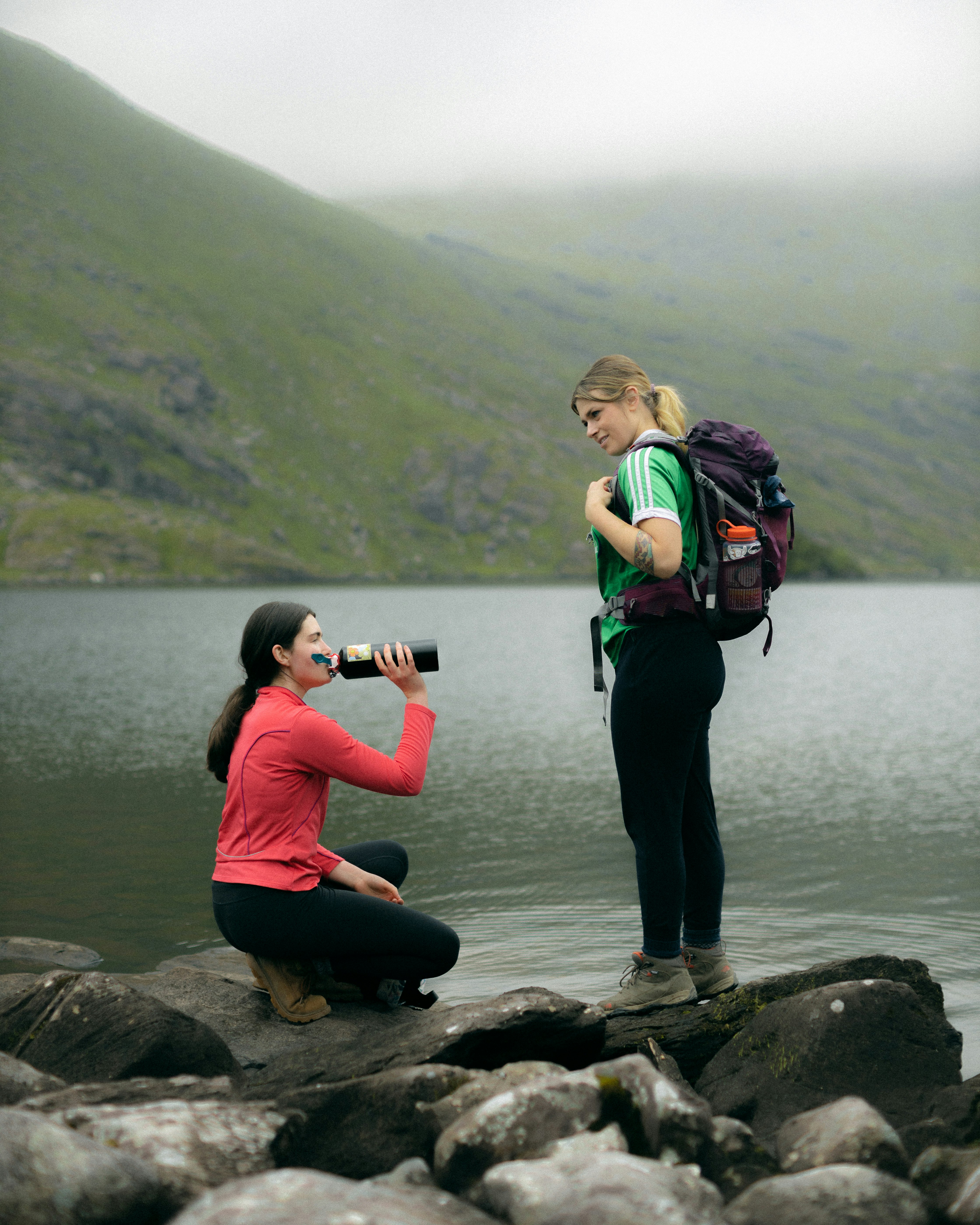 woman in green jacket and black pants holding black dslr camera